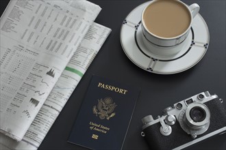 Passport, coffee, old camera and newspapers lying on table