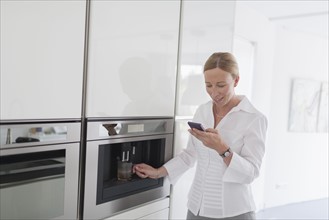 Woman using phone in kitchen