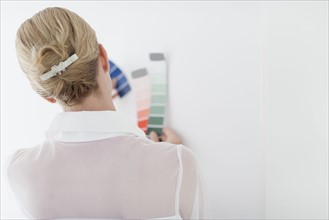 Woman comparing color swatch with white wall