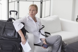 Businesswoman waiting with suitcase in hotel lobby