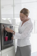 Mature woman preparing coffee in modern kitchen