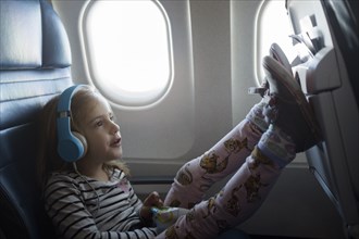 Girl wearing headphones on airplane