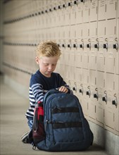 Boy with backpack by school lockers
