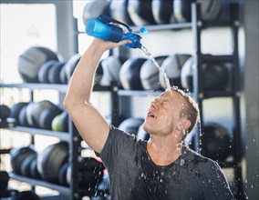 Man pouring water on himself in gym