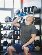 Mid adult man drinking in gym