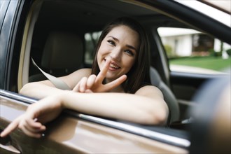 Smiling young woman doing peace sign in car