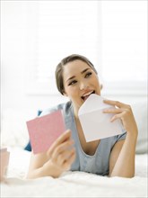 Woman licking envelope on bed