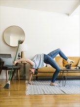 Woman bending over backwards sweeping and dusting