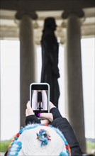 Woman taking photograph of statue with smart phone