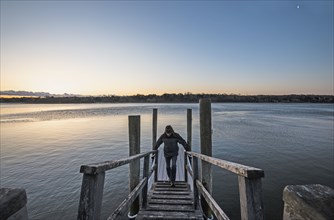 Man standing on pier at dawn