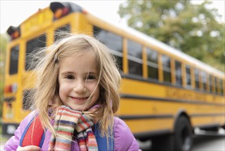 Smiling girl by school bus