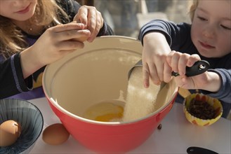 Children pouring ingredients into bowl