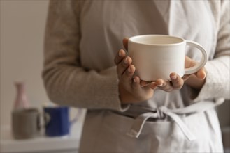 Hands of young woman holding coffee cup