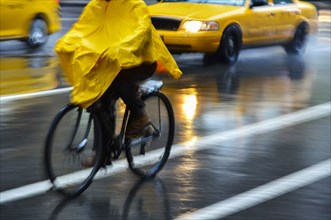 Cyclist in yellow poncho during rain in New York City, USA