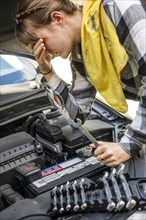 Frustrated woman repairing car