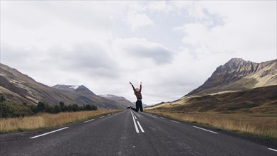 Woman jumping on highway in Iceland