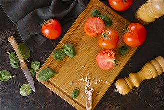 Tomatoes, basil and salt on wooden cutting board