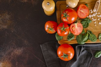 Tomatoes, basil and salt on wooden cutting board