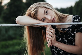 Young woman leaning on metal fence