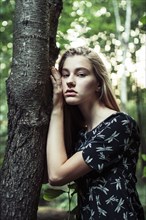 Young woman leaning on tree trunk
