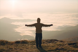 Man with arms outstretched in the Carpathian Mountain Range at sunrise