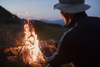 Man crouching by campfire