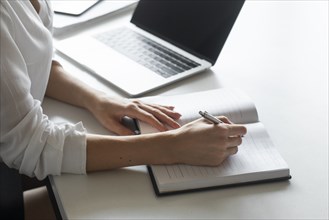 Hand of young businesswoman writing notes at desk