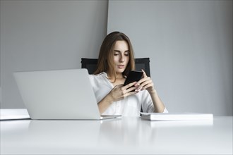Young businesswoman text messaging at desk