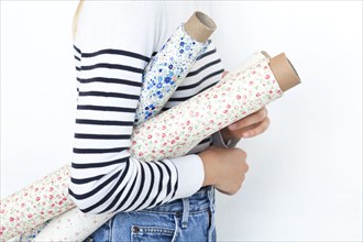 Arm of woman holding rolls of floral pattern fabric