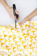 Hands of woman cutting fabric with duck print