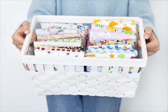 Woman's hands holding basket of fabrics