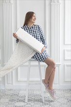 Woman sitting on stool unrolls fabric