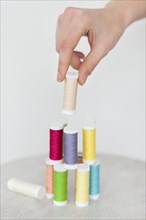 Hand of woman stacking colorful spools of thread