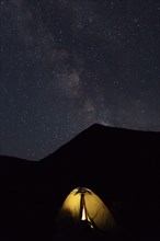 Illuminated tent by mountain at night