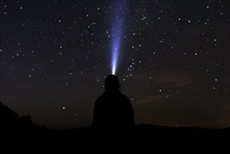 Silhouette of man with headlamp at night