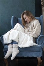 Smiling woman witting in armchair with white blanket
