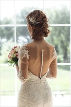 Bride with bouquet by window