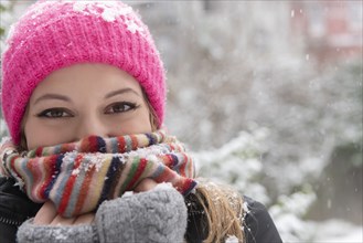 Portrait of young woman wearing woolly hat and scarf in snow