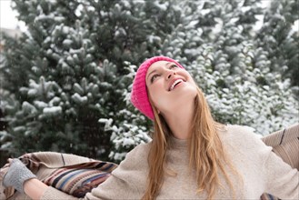 Young woman wearing woolly hat looking up in snow