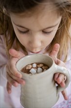 Girl blowing on hot chocolate