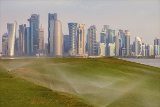 Sprinkler system on lawn by skyline of Doha, Qatar