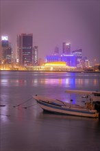 Moored motorboat by city skyline at night in Manama, Bahrain