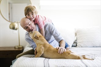 Father and son on bed with their dog