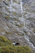 Waterfall above building in Milford Sound, New Zealand
