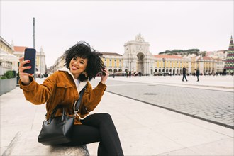 Young woman taking selfie in town square in Lisbon, Portugal