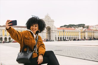 Young woman taking selfie in town square in Lisbon, Portugal
