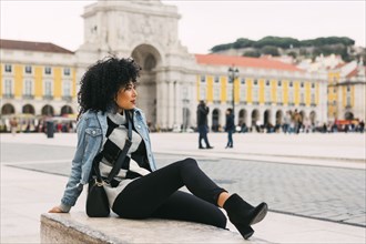 Young woman sitting in town square in Lisbon, Portugal
