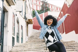 Young woman with her arms raised on staircase in Lisbon, Portugal