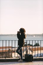 Young woman taking photograph by railing