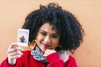 Portrait of young woman holding photograph of herself